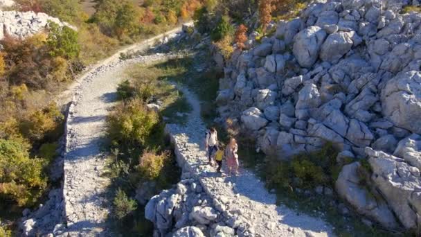 Tembakan udara. Dron mengikuti keluarga seorang wanita pria dan putra mereka saat mereka berjalan ke atas bukit menuju Benteng Kosmach di Montenegro. Sebuah benteng tua yang dibangun oleh Austria sebagai struktur pertahanan — Stok Video