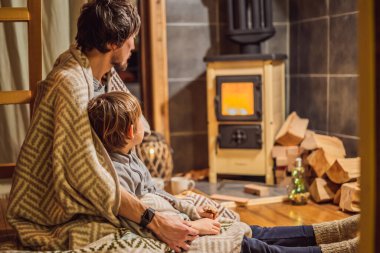 Baba ve oğlu Glamping 'de şöminenin yanında vakit geçiriyorlar. Glamping 'deki dağlarda dinlen. Dağ evinde sıcacık şömine