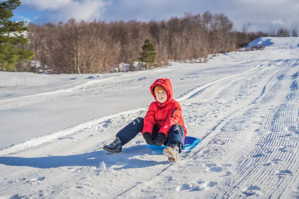 Menino pequeno feliz e positivo apreciando trenó e frio tempo ao ar livre, conceito de atividade divertida de inverno — Fotografia de Stock