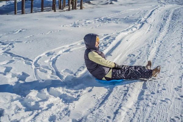 Šťastná žena se baví při sjezdu z horského svahu na saních. Zimní sporty se sněhem. Lidé na saních — Stock fotografie