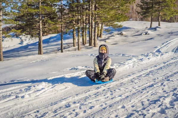 Mulher feliz se divertindo durante rolar pela encosta da montanha no trenó. Esportes de inverno com neve. Pessoas montando um trenó — Fotografia de Stock