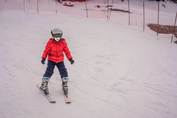 Ski d'enfant en montagne. Enfant tout-petit actif avec casque de sécurité, lunettes et bâtons. Course de ski pour jeunes enfants. Sport d'hiver pour la famille. Cours de ski pour enfants à l'école de ski alpin. Petit skieur de course dans la neige — Photo