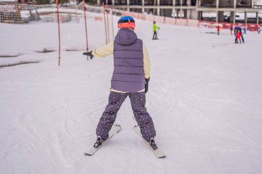 Kayak öğrenen bir kadın. Genç bir kadın dağlarda karlı bir yolda kayak yapıyor.