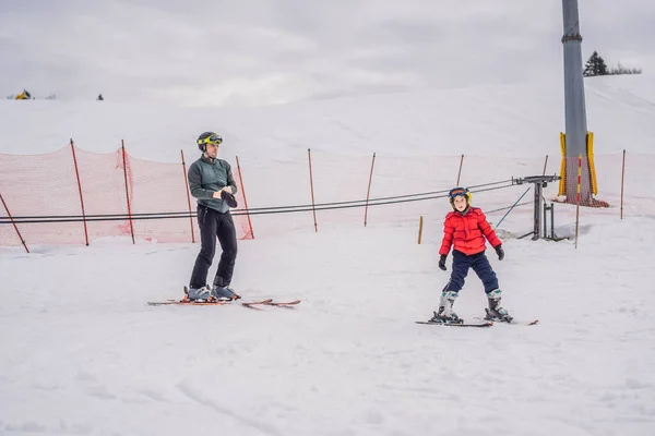Мальчик учится кататься на лыжах, тренироваться и слушать своего лыжного инструктора на склоне зимой — стоковое фото