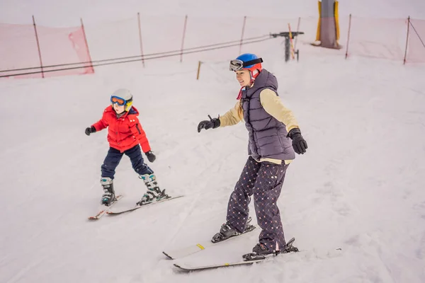 Mom and little boy mountain ski standing on top of the peak piste with high mountains on background — Stock Photo, Image