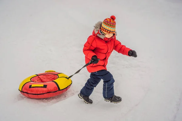 Dítě se baví na sněhové trubici. Ten kluk jezdí na trubkách. Zimní zábava pro děti — Stock fotografie