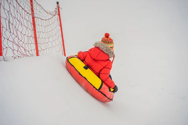 Dziecko bawiące się na snowtubie. Chłopak jedzie na rurze. Zimowa zabawa dla dzieci — Zdjęcie stockowe