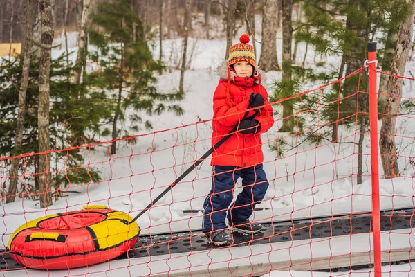 Το αγόρι με τις σωληνώσεις ανεβαίνει σε έναν ταξιδιώτη στο βουνό. Το παιδί διασκεδάζει στο χιόνι. Το αγόρι καβαλάει ένα σωλήνα. Χειμερινή διασκέδαση για παιδιά — Φωτογραφία Αρχείου