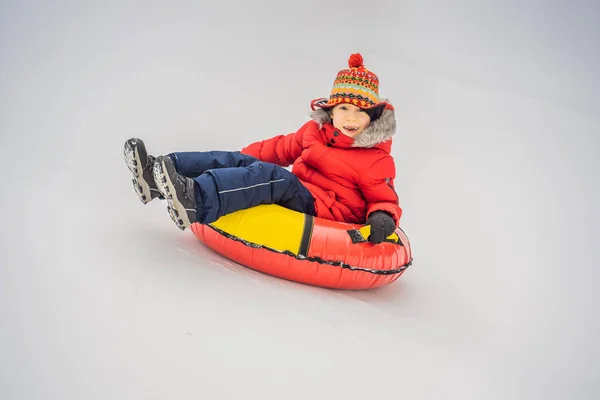 Enfant qui s'amuse sur un tube à neige. Le garçon monte dans un tube. Amusement d'hiver pour les enfants — Photo