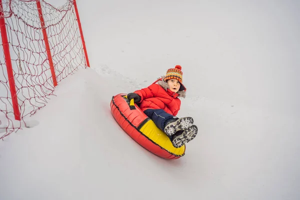 Das Kind hat Spaß auf der Schneekanone. Junge reitet auf einem Schlauch. Winterspaß für Kinder — Stockfoto