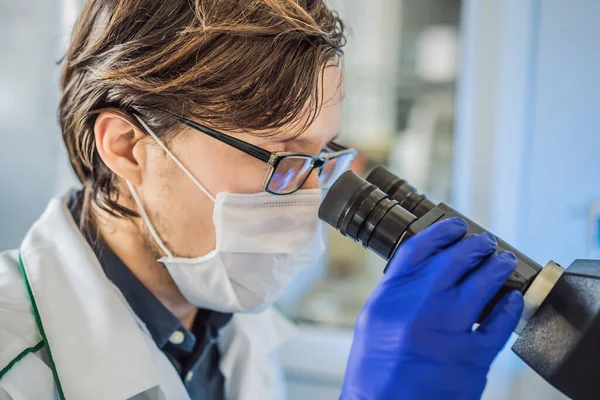 Portrait of caucasian male chemist scientific researcher using microscope in the laboratory interior coronavirus — Stock Photo, Image