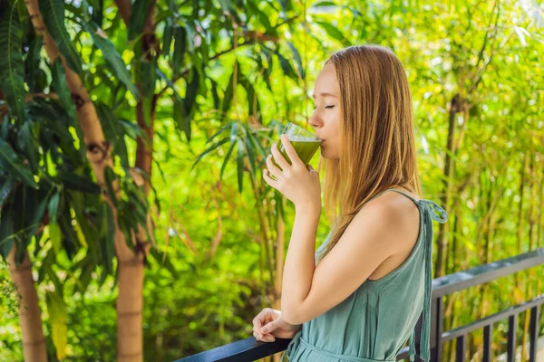 Молодая женщина пьет сок сельдерея, здоровый напиток, кучу сельдерея на деревянном фоне — стоковое фото