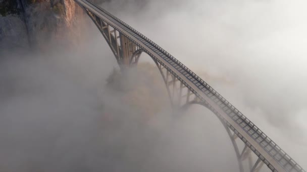 黑山北部塔拉河峡谷上宏伟的朱迪耶维奇桥的空中录像。美丽的晨雾穿过桥的拱门.在秋天拍的 — 图库视频影像