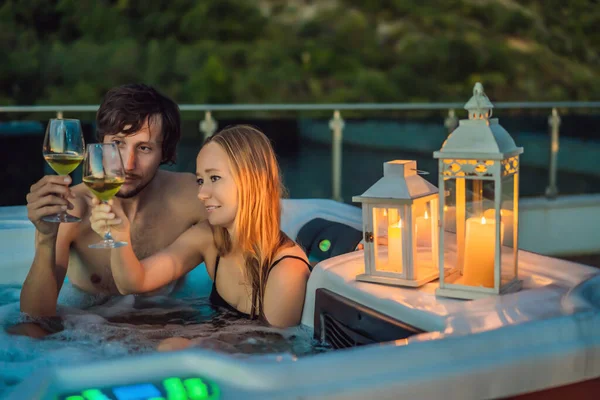 Retrato de joven despreocupada feliz pareja sonriente relajarse en la bañera de hidromasaje durante el disfrute de la vida feliz viaje momento de vacaciones en el fondo de grandes montañas verdes —  Fotos de Stock