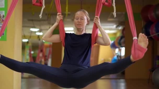 Een jonge vrouw oefent luchtyoga met behulp van speciale hangmatten — Stockvideo