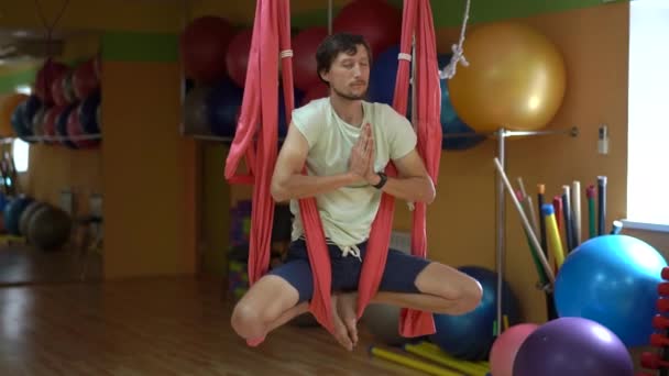 Un joven practica yoga aéreo usando hamacas especiales — Vídeos de Stock