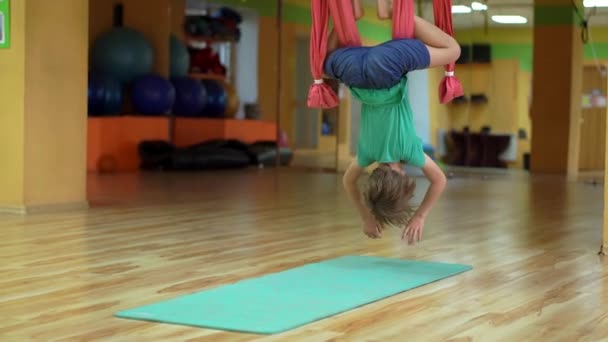 Pequeño niño practica yoga aéreo usando hamacas especiales — Vídeos de Stock