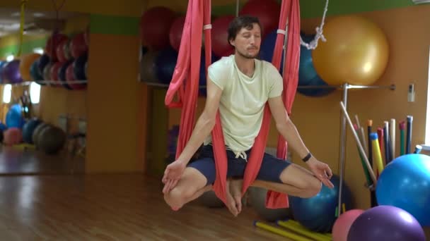 Ein junger Mann praktiziert Aerial Yoga mit speziellen Hängematten — Stockvideo