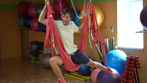 Un joven practica yoga aéreo usando hamacas especiales — Vídeos de Stock