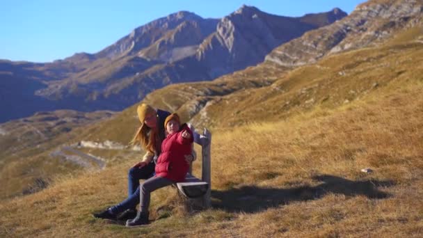 Семья туристов посещает перевал Седло, Бобов Кук в горах северной Черногории. Они сидят на деревянном беке. Выстрел осенью — стоковое видео