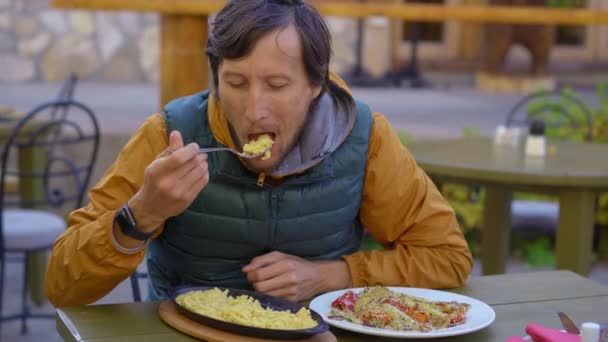 Турист посещает северную Черногорию. Он ест знаменитое северное блюдо под названием какамак из вареной картошки, кукурузы, сыра и молочных сливок. — стоковое видео