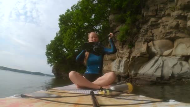 Una joven remando en una tabla de SUP entre rocas. Grabado en una cámara de acción — Vídeos de Stock