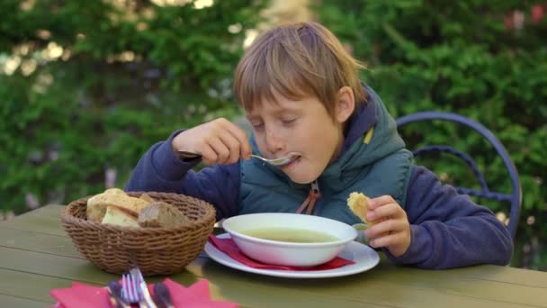 Een jongen in een café eet een soep — Stockvideo