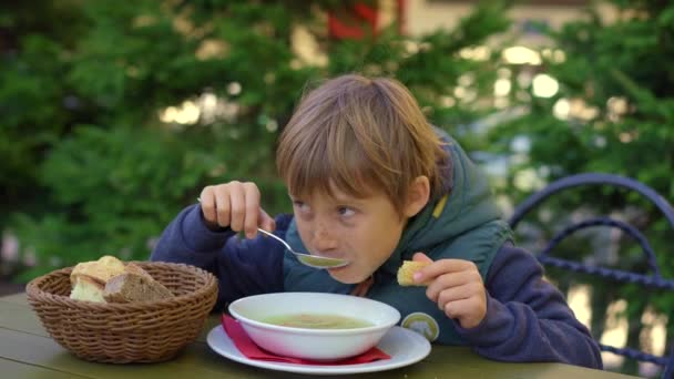 옥외 카페에 있는 한 소년 이 수프를 먹고 있다 — 비디오