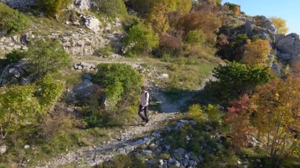 Letecký záběr. Drone následuje muže, jak sestupuje z kopce směrem od pevnosti Kosmach v Černé Hoře. Stará pevnost postavená Rakušany jako obranná stavba a vyhlídkové místo — Stock video