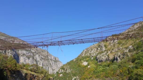Un video aereo. Un vecchio ponte di corda metallica attraverso il canyon del fiume Moraca in Montenegro — Video Stock