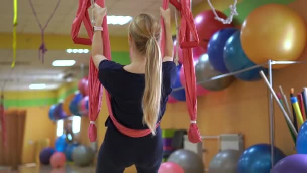 Een jonge vrouw oefent luchtyoga met behulp van speciale hangmatten — Stockvideo