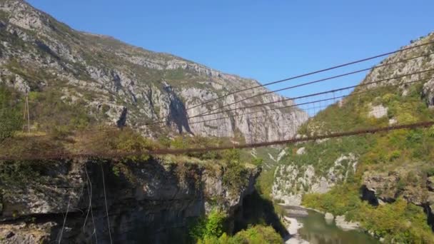 Vídeo aéreo. Un viejo puente de cuerda metálica sobre el cañón del río Moraca en Montenegro — Vídeo de stock