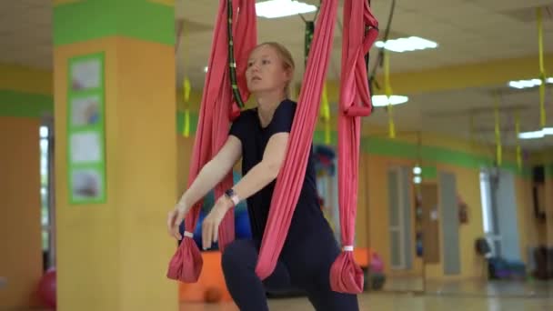 Een jonge vrouw oefent luchtyoga met behulp van speciale hangmatten — Stockvideo