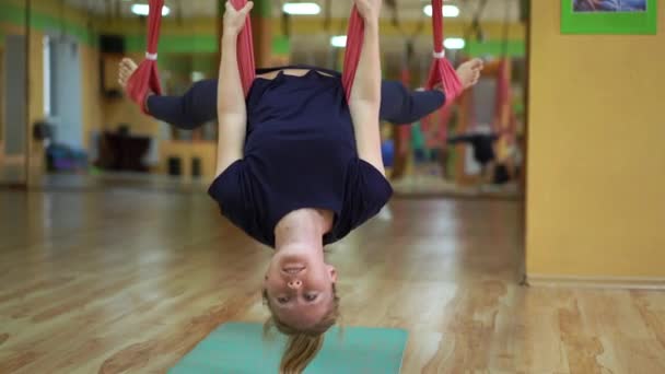 Une jeune femme pratique le yoga aérien en utilisant des hamacs spéciaux — Video