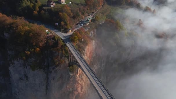 黑山北部塔拉河峡谷上宏伟的朱迪耶维奇桥的空中录像。美丽的晨雾穿过桥的拱门.在秋天拍的 — 图库视频影像