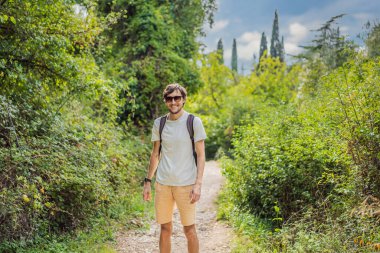 Sırt çantalı bir adam yol boyunca yürüyor. Yaya yolundaki adam mı? Arkadaki adam. Adam işe gidiyor.