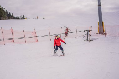 Çocuk dağlarda kayak yapıyor. Güvenlik kaskı, gözlüğü ve direkleri olan aktif bir çocuk. Küçük çocuklar için kayak yarışı. Aile için kış sporu. Alp okulunda çocuklar kayak dersi alıyor. Küçük kayakçı karda yarışıyor