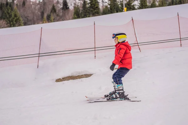 Παιδικό σκι στα βουνά. Ενεργό παιδί νηπίων με κράνος ασφαλείας, γυαλιά και κοντάρια. Αγώνας σκι για μικρά παιδιά. Χειμερινό άθλημα για την οικογένεια. Μαθήματα σκι για παιδιά σε αλπική σχολή. Μικρή σκιέρ αγωνιστικά στο χιόνι — Φωτογραφία Αρχείου