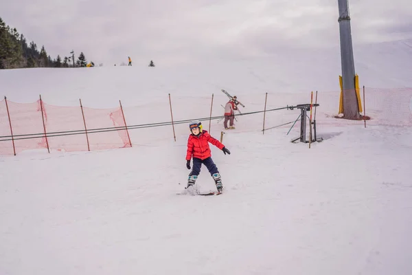 Esquí infantil en las montañas. Niño activo con casco de seguridad, gafas y bastones. Carrera de esquí para niños pequeños. Deportes de invierno para la familia. Clases de esquí para niños en la escuela alpina. Pequeño esquiador corriendo en la nieve — Foto de Stock