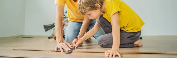 BANNER, FORMATO LUNGO Padre e figlio l'installazione di nuovi pavimenti in laminato di legno su un pavimento caldo pellicola. Sistema di riscaldamento a pavimento a infrarossi sotto pavimento in laminato — Foto Stock