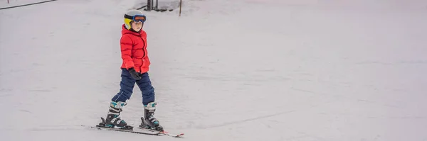BANNER, LONG FORMAT Ski pour enfants en montagne. Enfant tout-petit actif avec casque de sécurité, lunettes et bâtons. Course de ski pour jeunes enfants. Sport d'hiver pour la famille. Cours de ski pour enfants à l'école de ski alpin. Peu — Photo