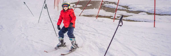 BANNER, LONG FORMAT Criança a esquiar nas montanhas. Criança ativa com capacete de segurança, óculos e postes. Corrida de esqui para crianças pequenas. Desporto de inverno para a família. Aula de esqui para crianças na escola alpina. Pouco. — Fotografia de Stock