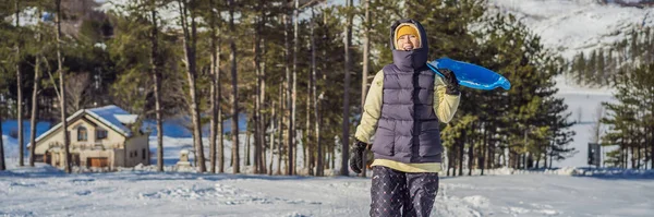 BANNER, LONG FORMAT Szczęśliwa kobieta bawiąca się podczas toczenia w dół zbocza góry na sankach. Sporty zimowe ze śniegiem. Ludzie jeżdżący na sankach — Zdjęcie stockowe