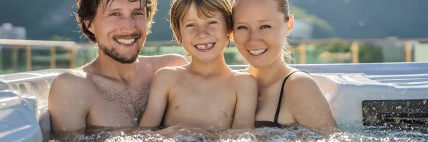 BANNER, FORMATO LARGO Retrato de jóvenes despreocupados felices sonriendo feliz familia relajándose en la bañera de hidromasaje durante el disfrute de felices vacaciones momento de viaje. La vida en el fondo de grandes montañas verdes — Foto de Stock