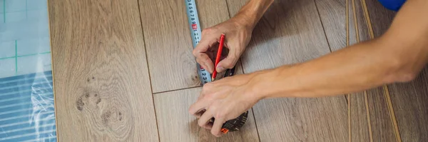 BANNER, LONG FORMAT Man instaluje nową drewnianą podłogę laminowaną na ciepłej podłodze z folii. System ogrzewania podłogowego na podczerwień pod podłogą laminowaną — Zdjęcie stockowe