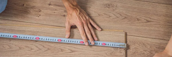 BANNER, LONG FORMAT Man installing new wooden laminate flooring on a warm film floor. Infrared floor heating system under laminate floor — Stock Photo, Image