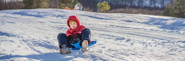 BANNER, LANG FORMAT Glücklicher und positiver kleiner Junge genießt Rodeln und Kälte im Freien, Winterspaß-Aktivitätskonzept — Stockfoto