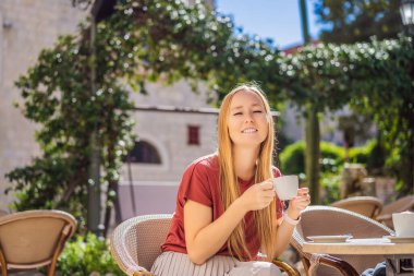Genç bayan turist, eski Budva kasabasında kahve içiyor. Karadağ 'a Seyahat