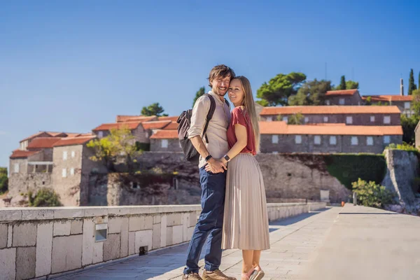 Homem e mulher turistas no fundo da bela vista da ilha de Santo Estêvão, Sveti Stefan no Budva Riviera, Budva, Montenegro. Viajar para Montenegro conceito — Fotografia de Stock