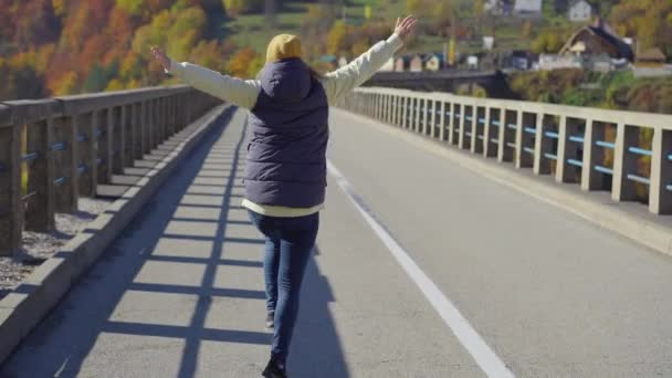 一名妇女游客参观了黑山北部塔拉河峡谷上宏伟的Djurdjevica桥。在秋天拍的。前往东欧的旅行概念 — 图库视频影像